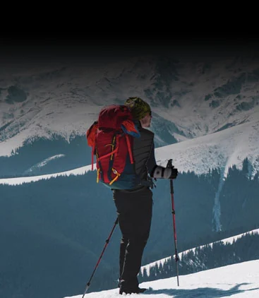 A hiker with poles on a snowy ridge