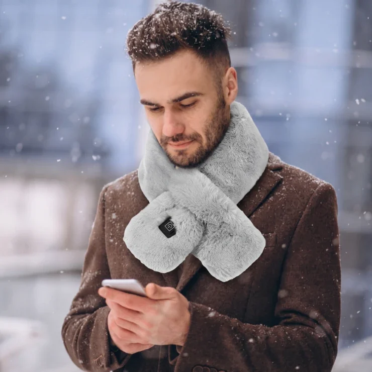A man wearing the grey Solana Gear Heated Scarf on a snowy street